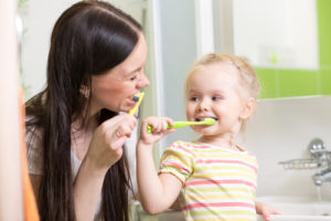 Mum teaching baby how to brush teeth